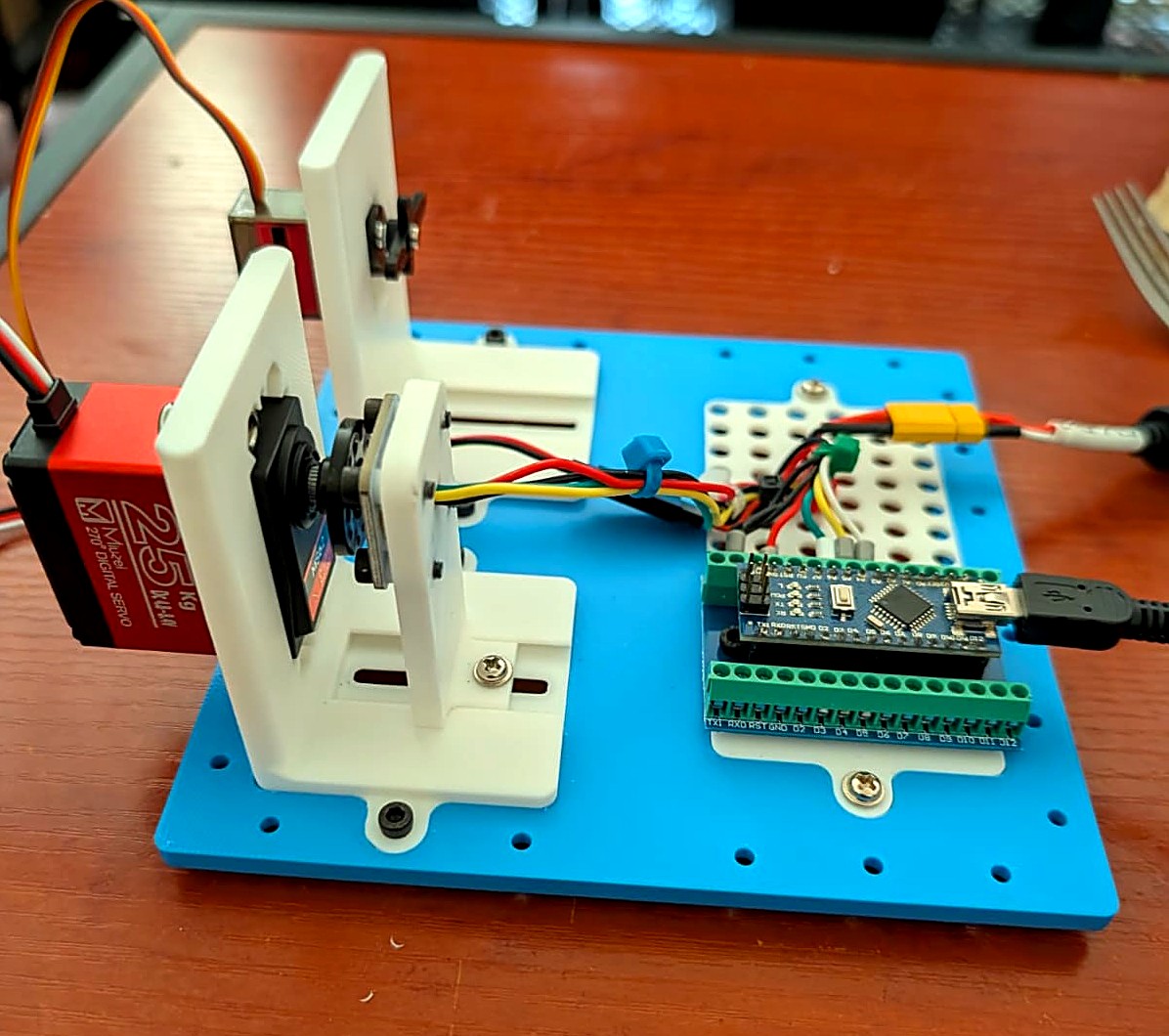 The physical test jig: a Miuzei 25kg Servo (left, red) with the AS5600 magnetic encoder mounted directly on its output shaft, and an MG90D (right), both bolted to a 3D-printed bracket, wired to an Arduino Nano clone on a screw-terminal breakout.